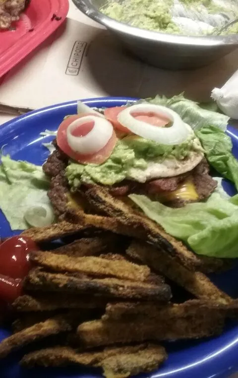 Bacon-Ei-Käse-Burger mit Tomate, Zwiebel und Avocado-Aufstrich in einem Salatblatt